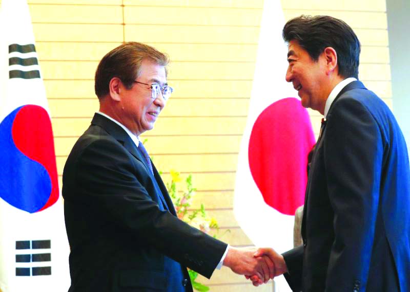 Japanese Prime Minister Shinzo Abe shaking hands with South Korean National Intelligence Service chief Suh Hoon on Tuesday.
