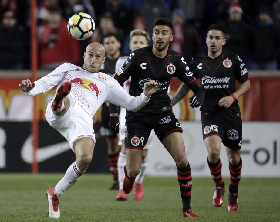 New York Red Bulls defender Aurelien Collin (front) tries to clear the ball away as Tijuana forward Juan Martin Lucero (center) and defender Damian Perez look on during the second half of a CONCACAF Champions League quarterfinal soccer match on Tuesday in