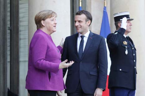 French President Emmanuel Macron greets German Chancellor Angela Merkel upon her arrival at the Eylsee presidential Palace in Paris on Friday.