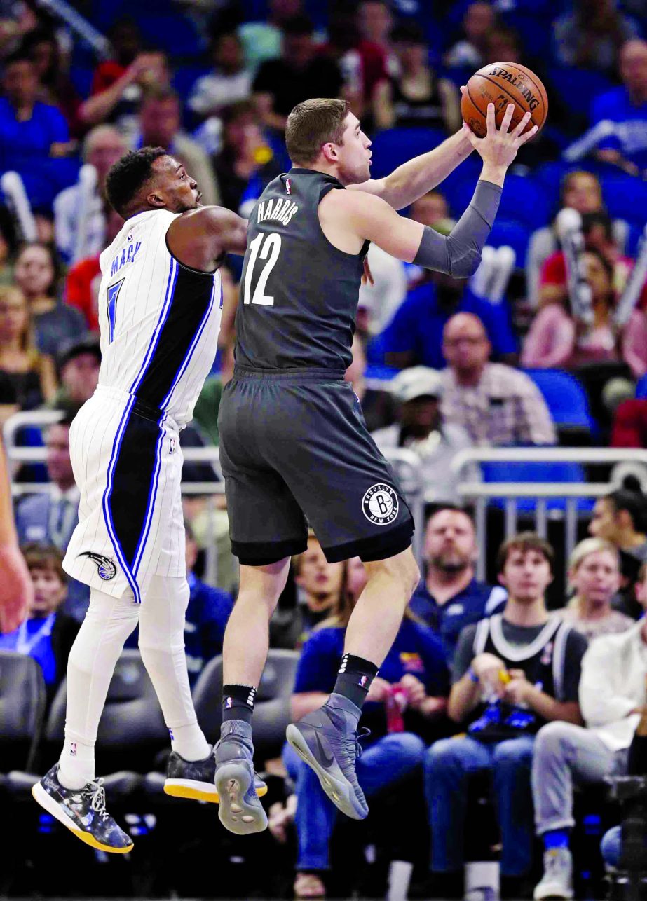 Brooklyn Nets' Joe Harris (12) gets off a shot in front of Orlando Magic's Shelvin Mack (left) during the first half of an NBA basketball game in Orlando, Fla. on Wednesday.