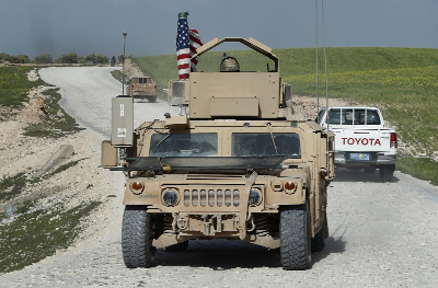U.S. troop's humvee passes vehicles of fighters from the U.S-backed Syrian Manbij Military Council on a road leading to the tense front line with Turkish-backed fighters, at Halawanji village, north of Manbij town, Syria.