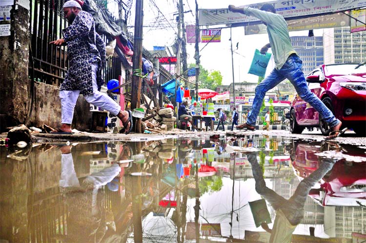 Locals and pedestrians crossing the waterlogging area at Topkhana's link road in city with difficulties. This photo was taken on Monday.