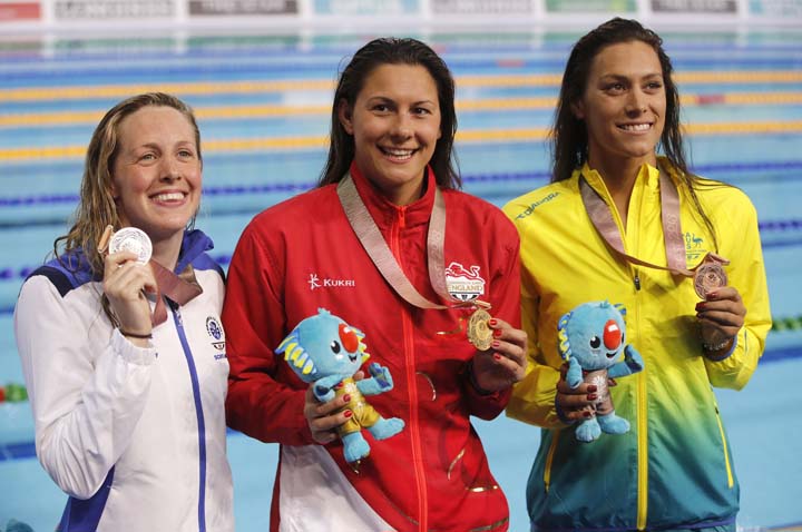 Women's 400m individual medley gold medalist England's Aimee Willmott, centre, stands with silver medalist Scotland's Hannah Miley, left, and bronze medalist Australia's Blair Evans, right, on the podium at the Aquatic Centre during the 2018 Commonw