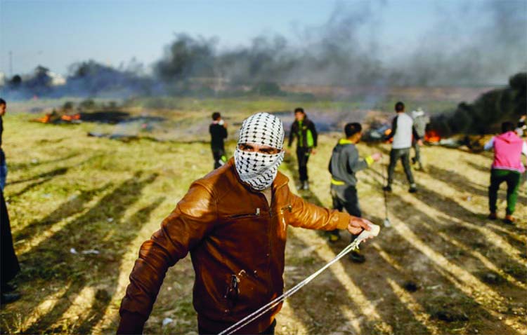 A Palestinian protestor uses a slingshot to throw a stone during clashes with Israeli forces at the Israel-Gaza border east of Gaza City.