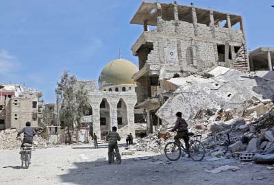 Syrian children ride their bike past destroyed buildings in the former rebel-held town of Zamalka, in Eastern Ghouta.