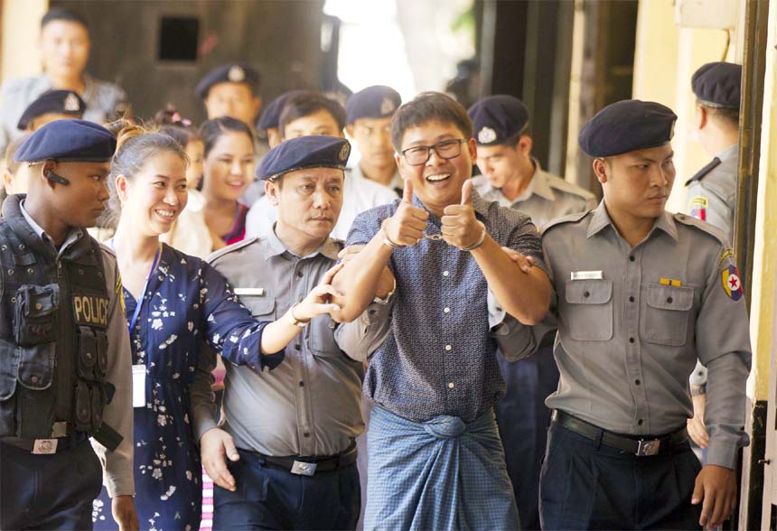 Reuters journalist Wa Lone( center), walks along with his wife Pan Ei Mon, second left, as he is escorted by police upon arrival at his trial on Wednesday in Yangon.