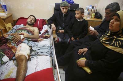 A Palestinian 25-year-old surfer, lies on a bed as his father, mother and brothers visit him, at the Shifa hospital in Gaza.