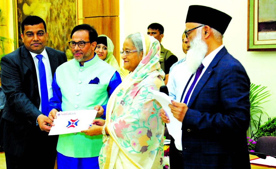 Prime Minister Sheikh Hasina is receiving a cheque of Tk. 1 crore for "Prime Minister's Relief and Assistance Fund" from Mohammed Mahtabur Rahman, Chairman of NRB Bank Limited at Gonabhaban on Friday. Mohammed Jahed Iqbal, Director of the bank among ot