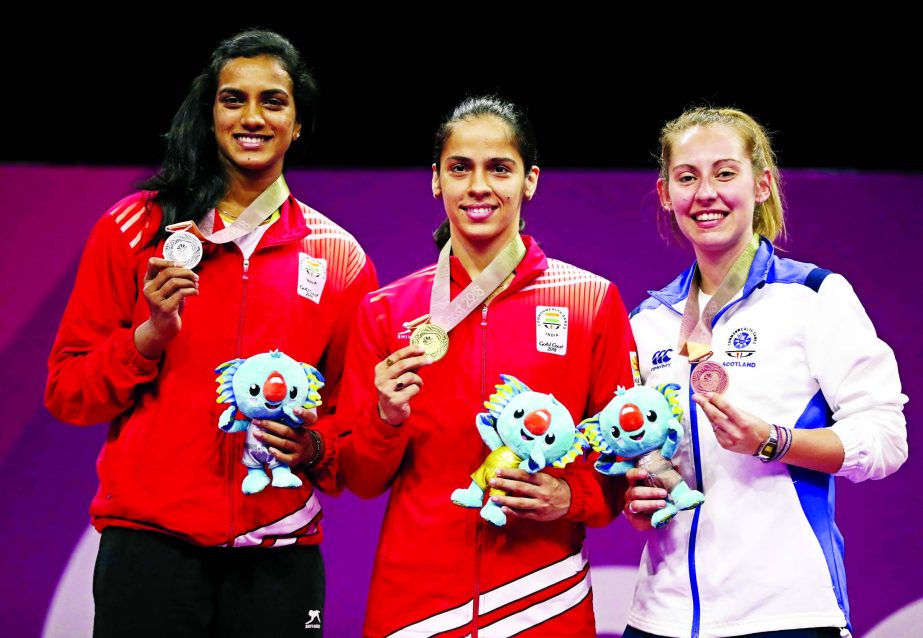 From left to right: Silver medalists Venkata Pusarla of India, gold medalists Saina Nehwal of India and bronze medalists Kirsty Gilmur of Scotland pose for photographers during the medal ceremony for women's singles badminton at Carrara Sports Hall durin