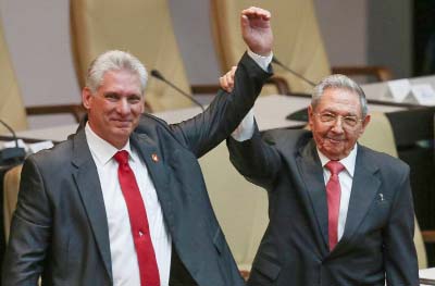 Cuba's outgoing President Raul Castro (right) and new President Miguel Diaz-Canel (Left) raise their arms in unison.