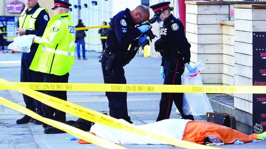 A police officer takes a picture of a covered body after a van struck multiple people at a major intersection northern in Canada on Monday. Internet photo