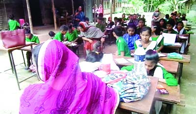 BETAGI(Barguna): Students of Bashanda Adarsha Primary School at Betagi Upazila attending examination under the open sky as the main school compound has been declared abandoned. This picture was taken yesterday.