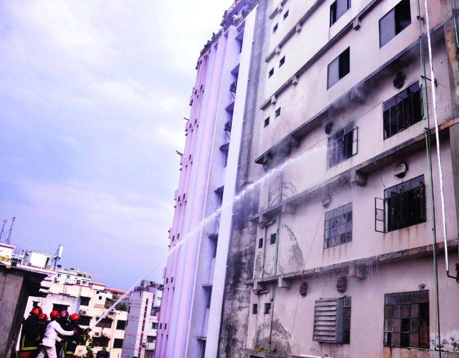 Fire fighters trying to control fire at a garments building at Rampura Hajipara area in the city yesterday .