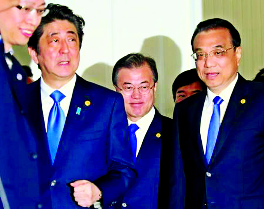 Chinese Premier Li Keqiang, Japanese Prime Minister Shinzo Abe and South Korean President Moon Jae-in walk together to their summit in Tokyo on Wednesday.