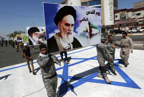 Supporters of Iraqi Hezbollah brigades march on a representation of an Israeli flag with a portrait of late Iranian leader Ayatollah Khomeini and Iran's supreme leader Ayatollah Ali Khamenei, in Baghdad.