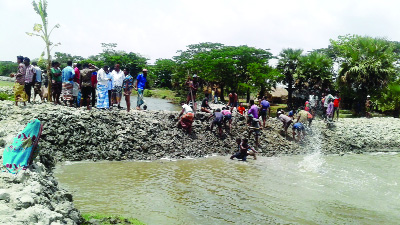 RANINAGAR (Patuakhali): Villagers at Raninagar Upazila cutting down the illegal dam over a canal between Char Lakkhai and Datbhanga area recently.