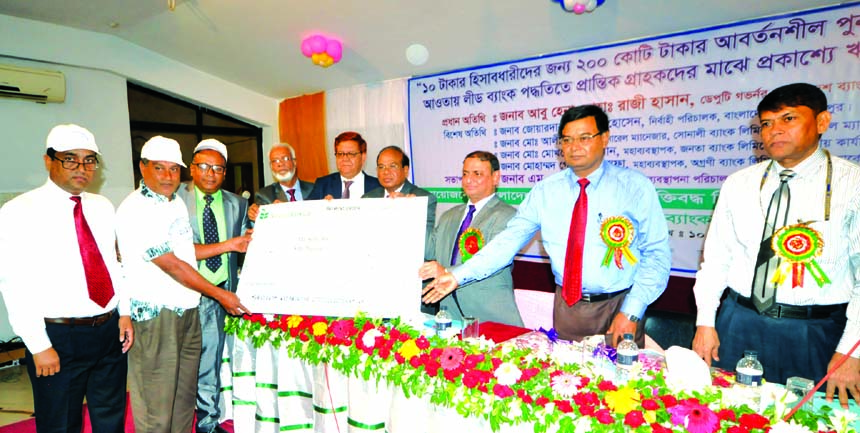 Abu Hena Mohd. Razee Hassan, Deputy Governor of Bangladesh Bank, handing over chaque of a 'Open loan disbursement in Dinajpur to 10 taka account-holders' organized by National Bank Limited (NBL) at a local auditorium recently as chief guest. MA Wadud, A