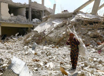 A woman gestures as she stands on rubble of damaged buildings in Raqqa, Syria