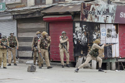 An Indian policeman fires a pellet gun at Kashmiri protesters in Srinagar, Indian controlled Kashmir on Friday