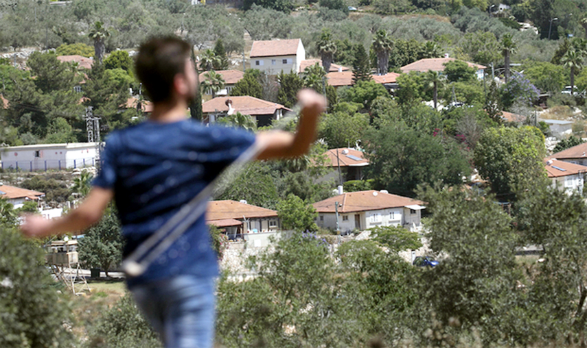 A Palestinian protester throws stones towards Qadumim, an Israeli settlement in the occupied West Bank.