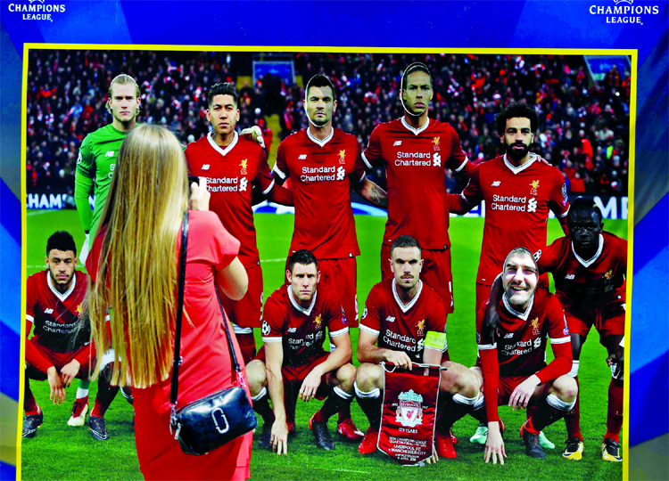A woman takes a photo of a banner depicting Liverpool team at a fan-zone in Kiev, Ukraine on Thursday. Liverpool will play Real Madrid in the Champions League Final today at the Olympiyski stadium in Kiev.
