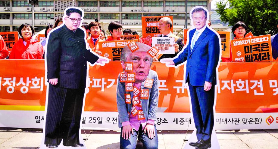 An anti-US protester wearing a face-mask depicting US president Donald Trump Â© kneels between cardboard cutouts of North Korean leader Kim Jong Un (L) and South Korean leader Moon Jae-in Â® during a rally calling for more dialogue between the three l