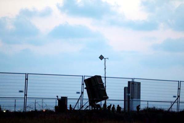Israeli soldiers walk next to an Iron Dome anti-missile system positioned near the city of Ashkelon, Israel on Tuesday.