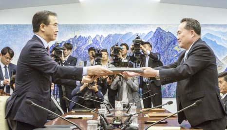 South Korean Unification Minister Cho Myoung-gyon, (left) and North Korean delegation head Ri Son Gwon exchange documents signed an agreement during their meeting inside the Peace House at the southern side of Panmunjom in the Demilitarized Zone on Friday