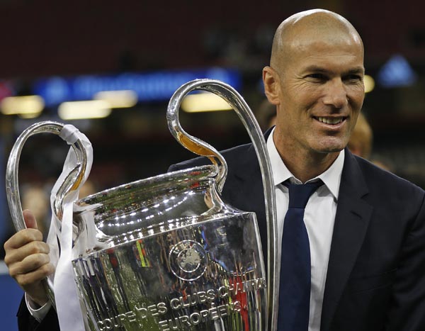 In this Saturday file photo Real Madrid's head coach Zinedine Zidane celebrates with the trophy at the end of the Champions League soccer final between Juventus and Real Madrid at the Millennium Stadium in Cardiff, Wales. Real won the match 4-1. Zidane s