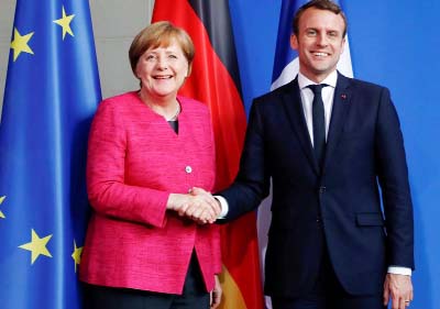 French President Emmanuel Macron shaking hands with German Chancellor Angela Merkel on his first day in office
