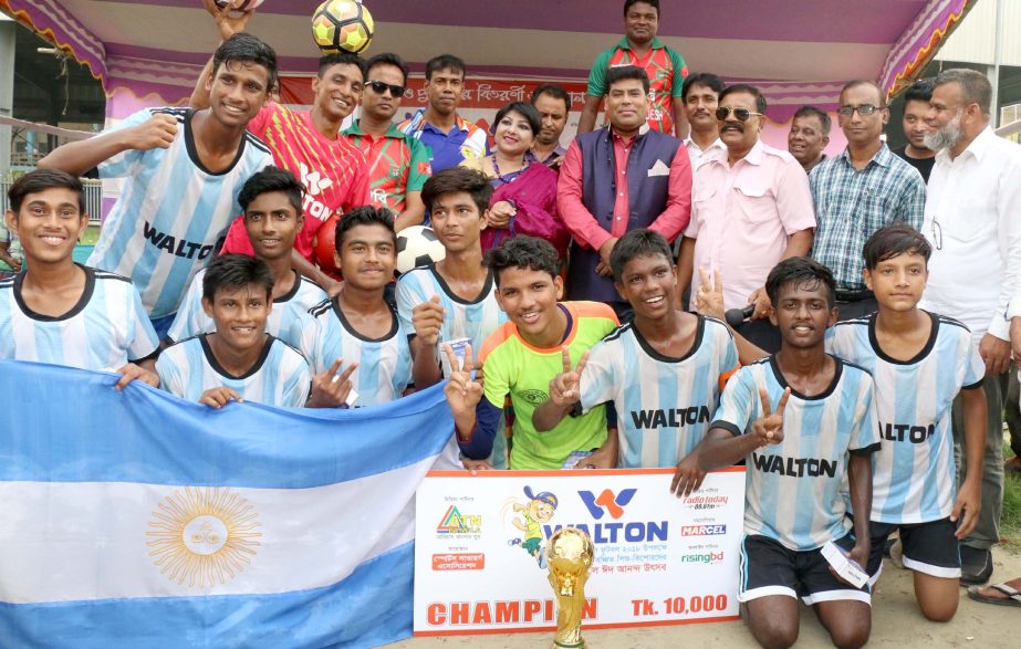Fun game: Argentina Football team, who became champion in the Walton football tournament for under privileged children pose for photo with the trophy and guests at the Paltan Maidan on Wednesday.