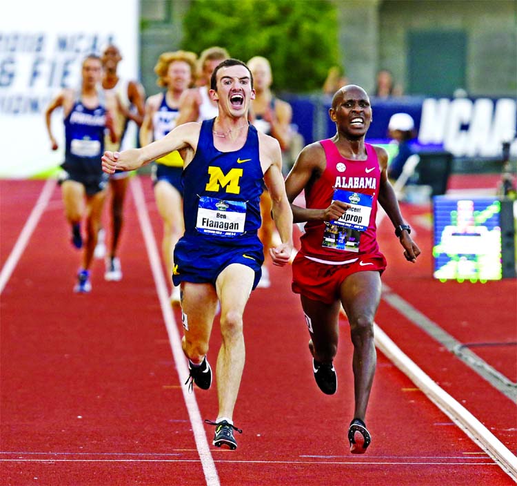 Michigan's Ben Flanagan begins to celebrate his NCAA title in the men's 10,000 meters as he passes Alabama's Vincent Kiprop near the finish line during the first day of the NCAA Outdoor Track and Field Championships on Wednesday at Hayward Field in Eug