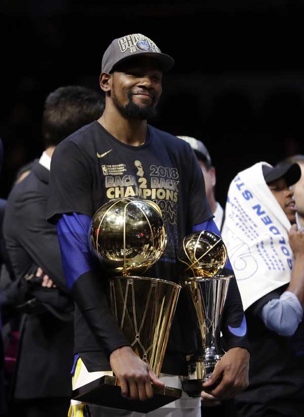 Golden State Warriors' Kevin Durant holds the NBA championship and MVP trophies after the Warriors defeated the Cleveland Cavaliers 108-85 in Game 4 of basketball's NBA Finals to win the NBA championship on Friday.
