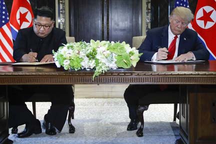 Kim Jong Un and Donald Trump sign documents after their meetings.