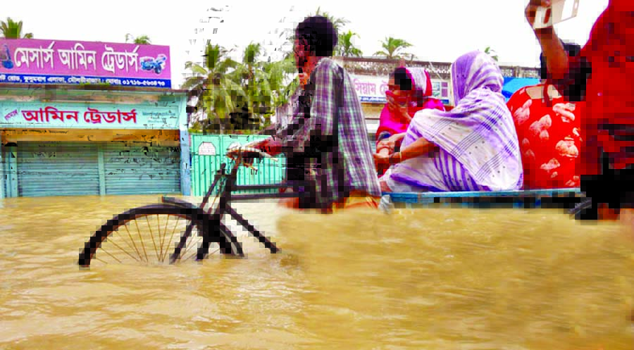 Due to heavy rain and on-rush of water from the upper-riparian areas of Moulvibazar have been inundated and the people are seen leaving their houses to safer places. This picture was taken from city's Kushumbagh area on Monday.