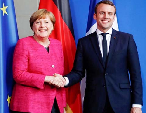 French President Emmanuel Macron shaking hands with German Chancellor Angela Merkel, at the G7 Summit in Canada, on Tuesday with EU reform and immigration top of the agenda.