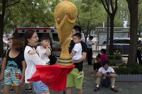 Huang Xin (seated bottom right) waits near the replica trophy he made from human hair in the likeness of the FIFA World Cup to coincide with the 2018 soccer World Cup held in Russia on the streets of Beijing, China on Monday. According to the artist Huang
