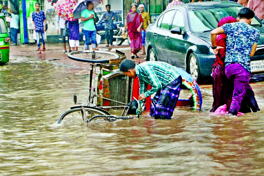 Motorized vehicles, rickshaws and also pedestrians struggle through the stagnated rain water as most of the city streets went under rain water yesterday. The snap was taken from the city's Shahjahanpur area.