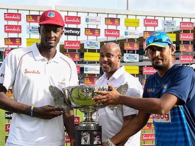 Jason Holder and Suranga Lakhmal receive the trophy from David Hinds.