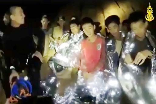 Several of the boys in the frame are wearing protective foil blankets and are accompanied by a smiling diver in a wetsuit, in video clips published on the Thai Navy SEAL