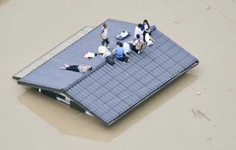 An aerial view shows local residents seen on the roof of submerged house at a flooded area as they wait for a rescue in Kurashiki, southern Japan. This photo was taken by Kyodo on Saturday.