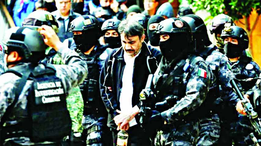 Accused drug kingpin Damaso Lopez, nicknamed "The Graduate", is escorted by police officers in Mexico City.