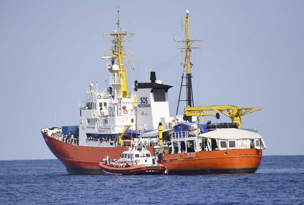 An Italian Coast Guard boat approaches the French NGO "SOS Mediterranee"" Aquarius ship as migrants are being transferred in the Mediterranean Sea."