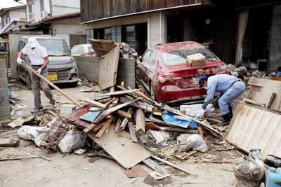 Local residents try to clear mud and debris at a flood affected area in Mabi town in Kurashiki, Okayama Prefecture on Friday.