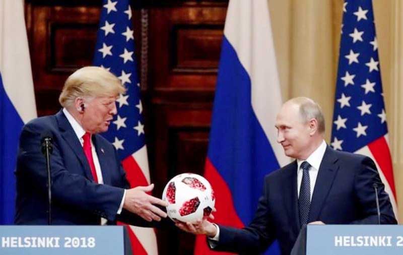 U.S. President Donald Trump receives a football from Russian President Vladimir Putin as they hold a joint news conference after their meeting in Helsinki.