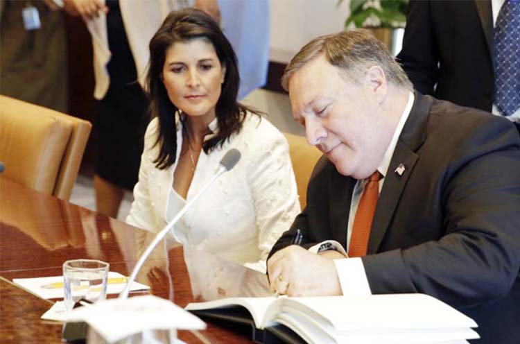 U.S. Secretary of State Mike Pompeo signs a guest book as he prepares for a meeting with United Nations Secretary General Antonio Guterres on Friday at the United Nations. U.S. Ambassador to the U.N. Nikki Haley, left, joins him for the meeting.