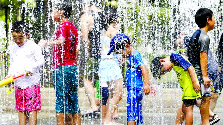Children cool themselves using water jets at a park in Tokyo.
