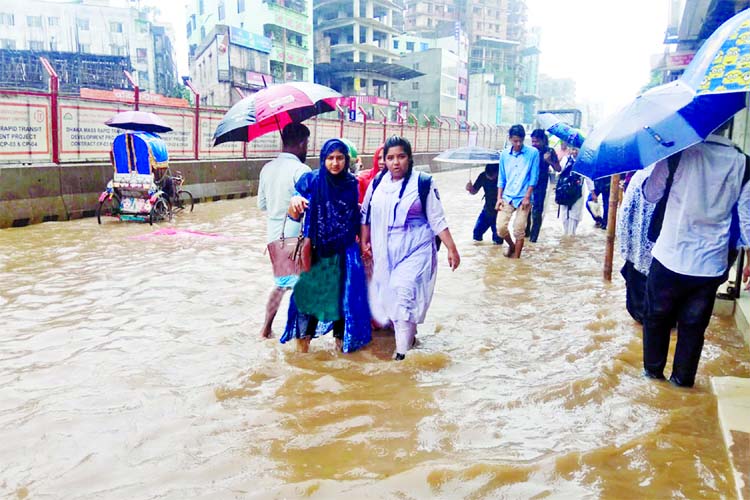 A busy thoroughfare in city's Mirpur was inundated by incessant rain since Sunday due to absence of proper drainage management. The photo taken on Wednesday shows people including women wading through knee-to-ankle deep water as the rain water remained