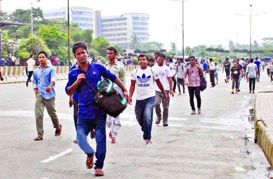 Office-goers walking on foot to reach their destination as buses remained off the roads due to students demonstration protesting Sunday's killing. This photo was taken from Airport Road on Tuesday.
