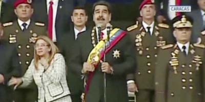 Presiden Nicolas Maduro, center, delivers his speech as his wife Cilia Flores winces and looks up after being startled by and explosion, in Caracas, Venezuela.